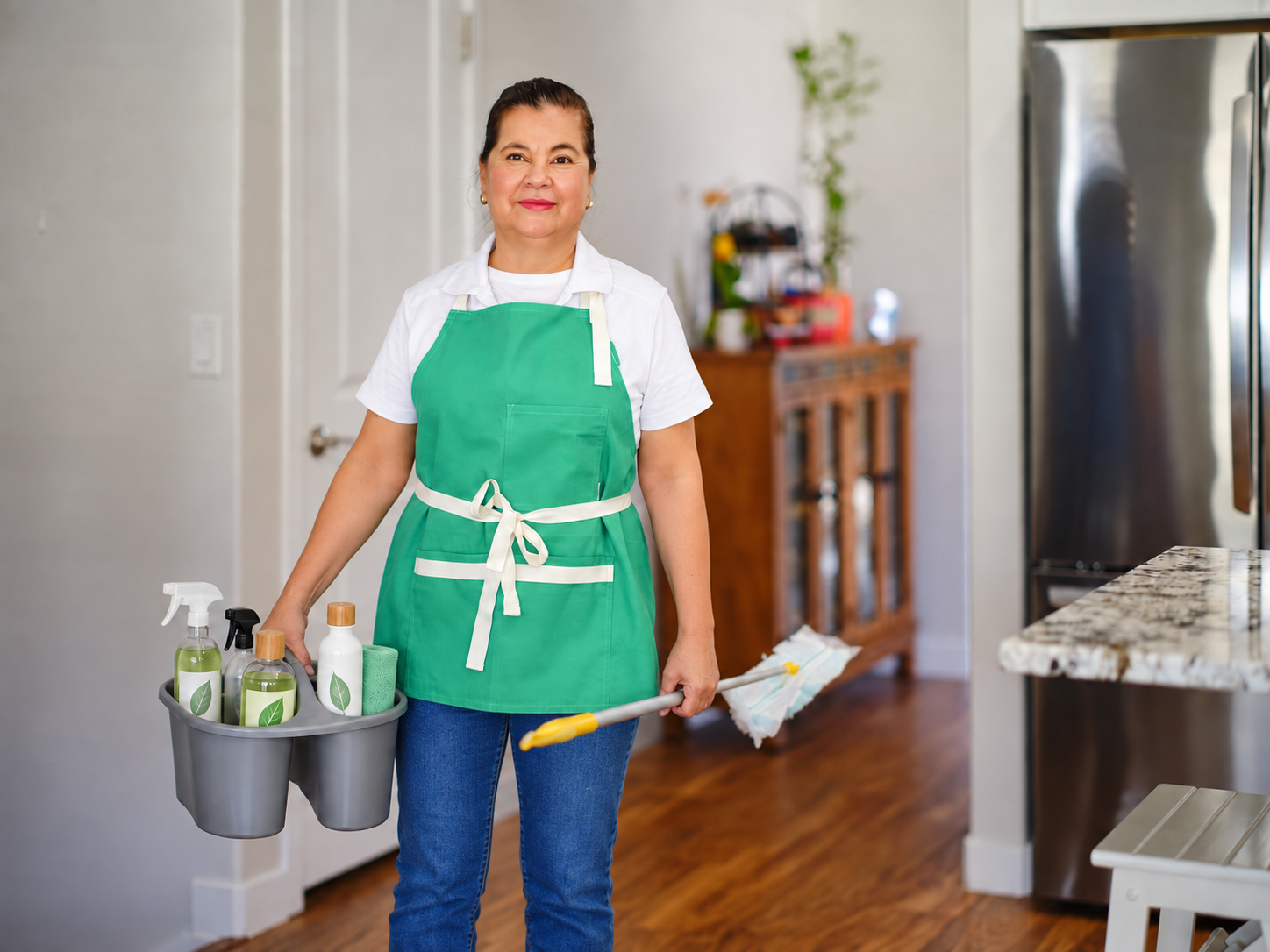 Cleaner in a turquoise apron holding eco-style supplies